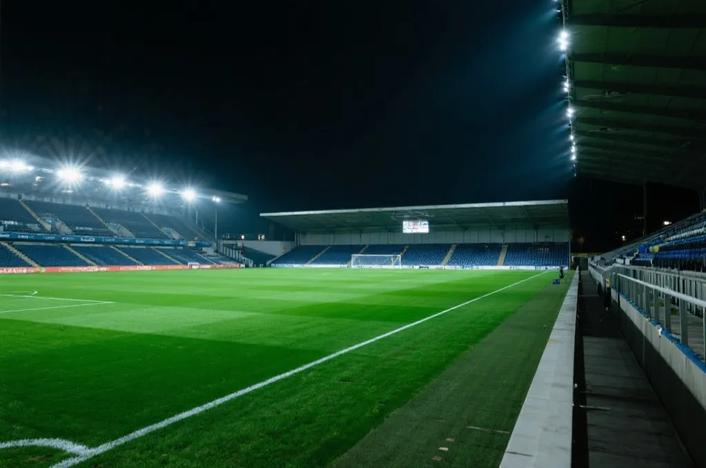A modern soccer stadium pitch under bright stadium lights, side view, dramatic atmosphere, high quality editorial photography